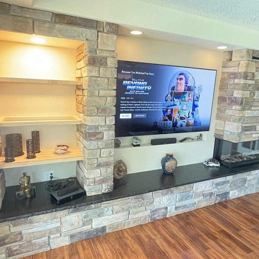 Stone entertainment wall with built-in shelving and fireplace